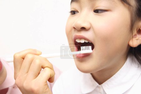 Téléchargez les photos : Asiatique petite fille avec une brosse à dents brossant ses dents - en image libre de droit