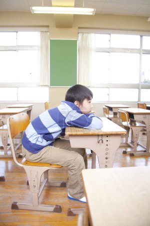 Photo for Bored Japanese school boy sitting in class - Royalty Free Image