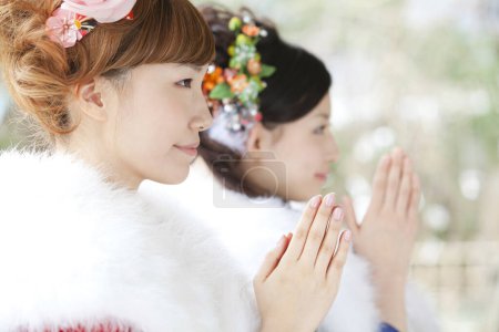 filles asiatiques habillées en furisode priant dans le temple
