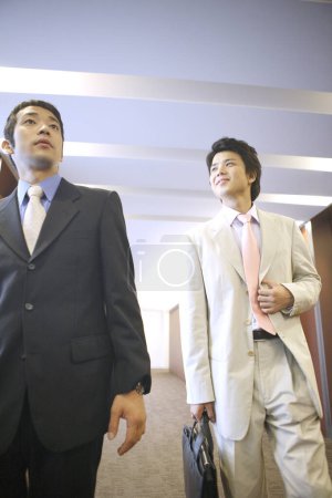 Téléchargez les photos : Deux jeunes hommes d'affaires marchant dans le bureau - en image libre de droit