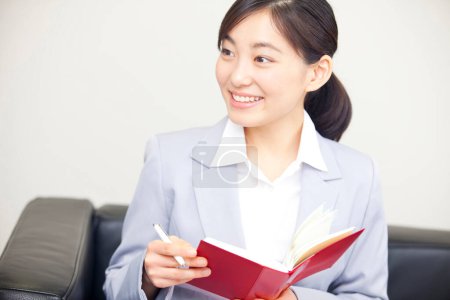 Foto de Una mujer en un traje de negocios sosteniendo un cuaderno - Imagen libre de derechos