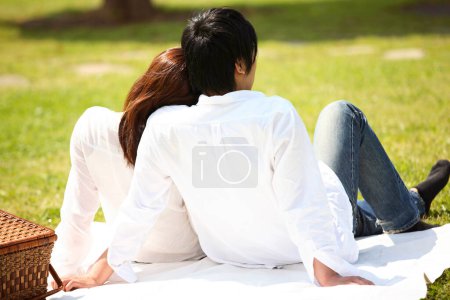 Téléchargez les photos : Un couple assis sur une couverture dans un parc - en image libre de droit