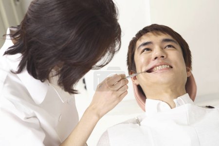 Photo for Young asian man getting his teeth treatment at dentist office - Royalty Free Image