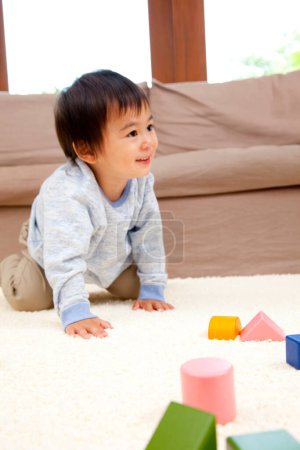 Foto de Asiático pequeño niño jugando en piso con madera juguetes - Imagen libre de derechos