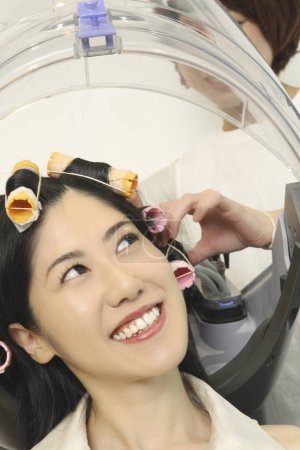 Foto de Retrato de mujer japonesa sonriente con rizadores de pelo en el salón de belleza - Imagen libre de derechos