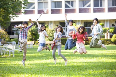 Photo for Happy group of students from music and sport sections jumping on green lawn - Royalty Free Image