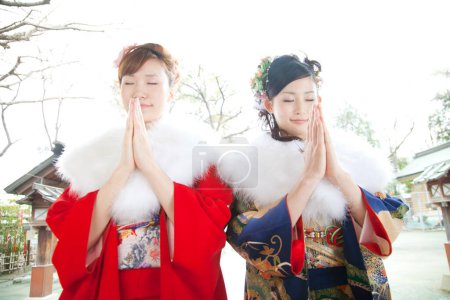 Foto de Retrato de hermosas mujeres japonesas en ropa tradicional rezando en el santuario - Imagen libre de derechos