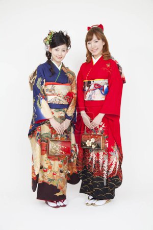 zwei junge asiatische Frauen in traditioneller Kleidung posieren auf weißem Studiohintergrund. traditioneller japanischer Stil
