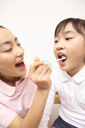 Téléchargez les photos : Japonais femelle dentiste enseignement mignon petite fille pour brosser dents - en image libre de droit