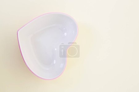 Téléchargez les photos : Un bol en forme de coeur sur une surface blanche - en image libre de droit