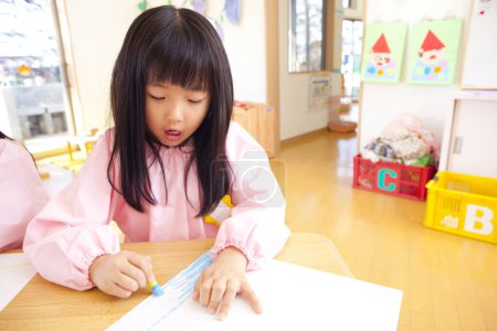 Téléchargez les photos : Mignonne petite fille dessine sur un morceau de papier - en image libre de droit