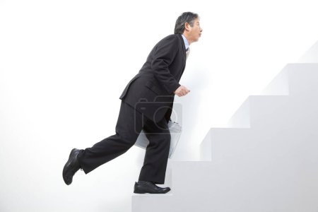 Téléchargez les photos : Un homme en costume montant un escalier - en image libre de droit