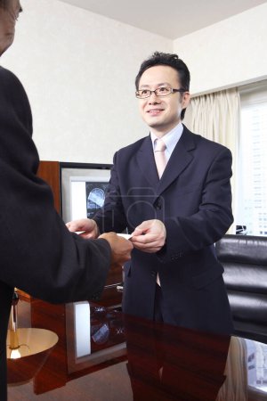 two confident japanese professors exchanging with visit cards in office