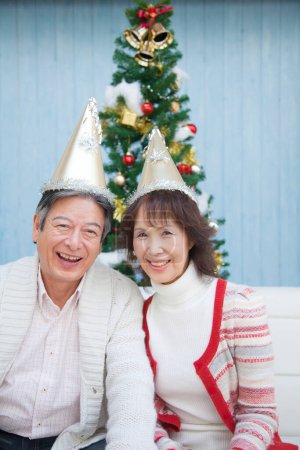 Photo for Asian senior  couple wearing party hats  celebrating Christmas at home - Royalty Free Image