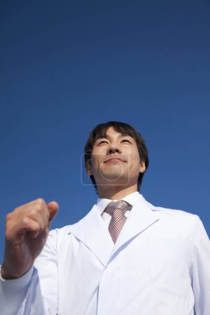 Téléchargez les photos : Un homme en blouse de laboratoire et cravate sur le fond du ciel - en image libre de droit