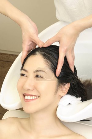 Photo for Portrait of smiling Japanese woman washing head at hairdresser - Royalty Free Image