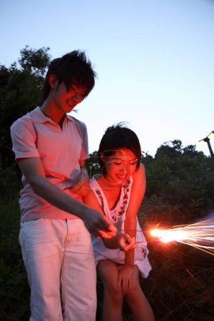 Téléchargez les photos : Heureux Japonais homme et femme tenant des étincelles dans leurs mains - en image libre de droit