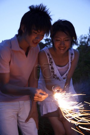 Photo for Happy Japanese man and woman holding sparklers in their hands - Royalty Free Image