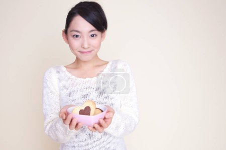 Foto de Hermosa mujer japonesa sosteniendo tazón con galletas - Imagen libre de derechos
