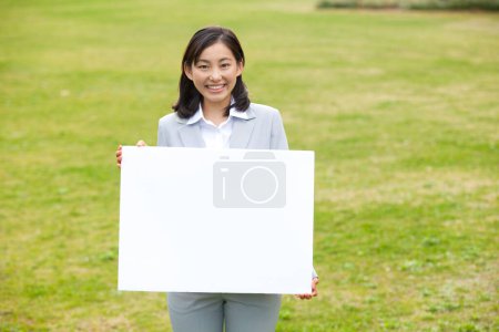 Foto de Una mujer sosteniendo un cartel en blanco en un parque - Imagen libre de derechos