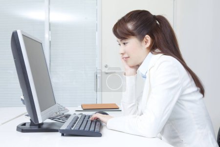 Téléchargez les photos : Jeune femme utilisant un ordinateur au bureau - en image libre de droit