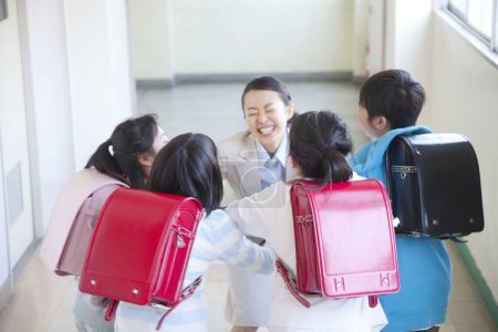 Photo for Happy schoolchildren with teacher in school corridor - Royalty Free Image