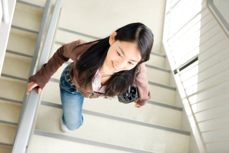 Photo for Young japanese female student walking on stairs in college - Royalty Free Image