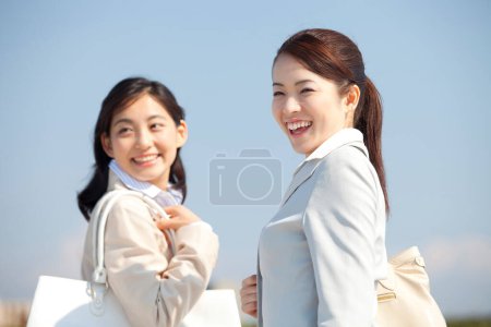 Photo for Two asian women are smiling and holding white bags - Royalty Free Image