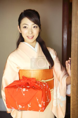 Foto de Retrato de una joven japonesa en kimono tradicional sosteniendo bento envuelto - Imagen libre de derechos