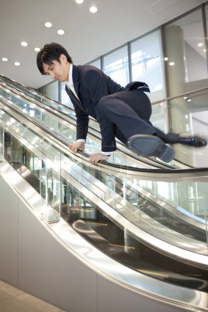 Téléchargez les photos : Jeune homme d'affaires sautant escalator - en image libre de droit