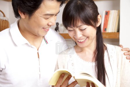 Téléchargez les photos : Couple lecture livre ensemble à la maison - en image libre de droit