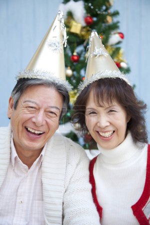 Photo for Asian senior  couple in party hats  Christmas at home - Royalty Free Image
