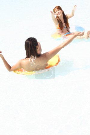 Téléchargez les photos : Jeunes femmes s'amusant sur des anneaux gonflables dans la piscine - en image libre de droit