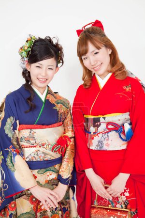 two young asian women in traditional clothing posing on white studio background. traditional japanese style