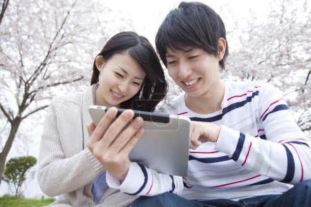 Téléchargez les photos : Jeune Japonais avec tablette numérique dans le parc - en image libre de droit