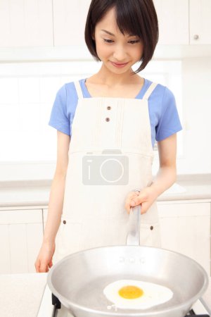 Foto de Hermosa asiática ama de casa cocina en cocina - Imagen libre de derechos