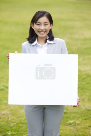 Photo for A woman holding a sign in a field - Royalty Free Image