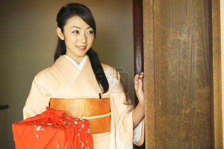 Téléchargez les photos : Portrait de jeune femme japonaise en kimono traditionnel tenant un bento enveloppé - en image libre de droit