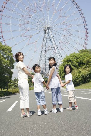 Téléchargez les photos : Mère heureuse et les enfants debout dans le parc d'attractions contre la roue ferris - en image libre de droit