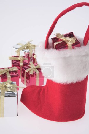 Téléchargez les photos : Chaussette santa claus avec des cadeaux sur un fond blanc - en image libre de droit