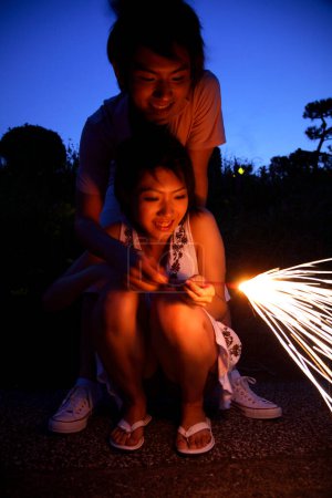 Téléchargez les photos : Heureux Japonais homme et femme avec scintillant dans la soirée - en image libre de droit