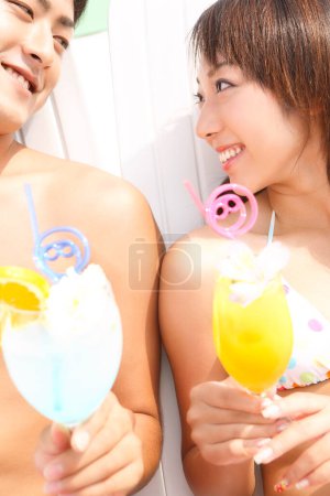 Photo for Young asian woman and man enjoying a summer cocktails - Royalty Free Image