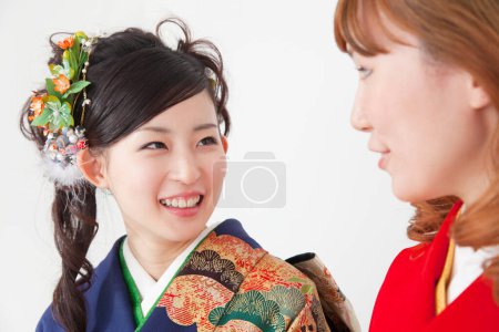 two young asian women in traditional clothing posing on white studio background. traditional japanese style