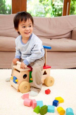 Foto de Asiático pequeño niño jugando en piso con madera juguetes - Imagen libre de derechos