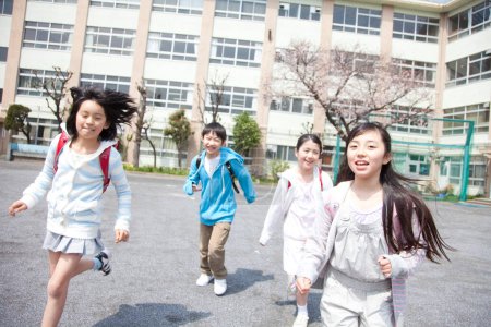 Foto de Grupo de alumnos de la escuela primaria feliz corriendo en el patio de la escuela - Imagen libre de derechos