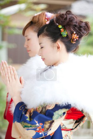 filles asiatiques habillées en furisode priant dans le temple
