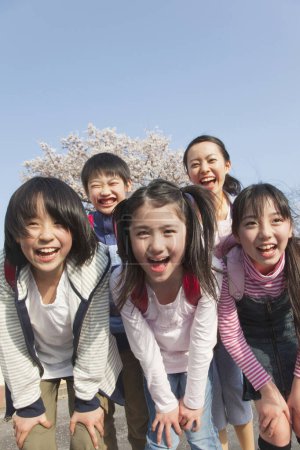 Foto de Niños japoneses sonrientes con mochilas en el parque de primavera - Imagen libre de derechos