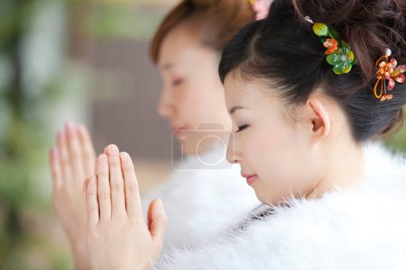 Asiático niñas vestidas en furisode orar en templo