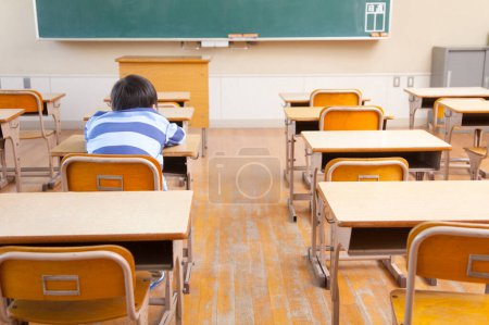 Téléchargez les photos : Jeune étudiant assis dans une salle de classe - en image libre de droit