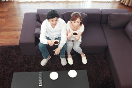 Téléchargez les photos : Un couple assis sur un canapé tenant des tasses de café - en image libre de droit